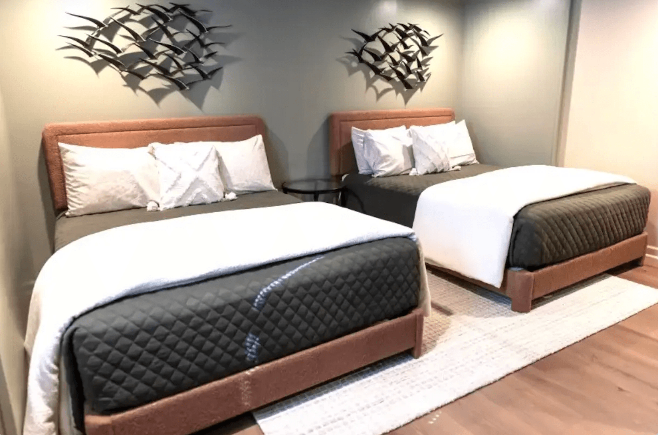 A cozy hotel room featuring two beds with decorative headboards and wall art.