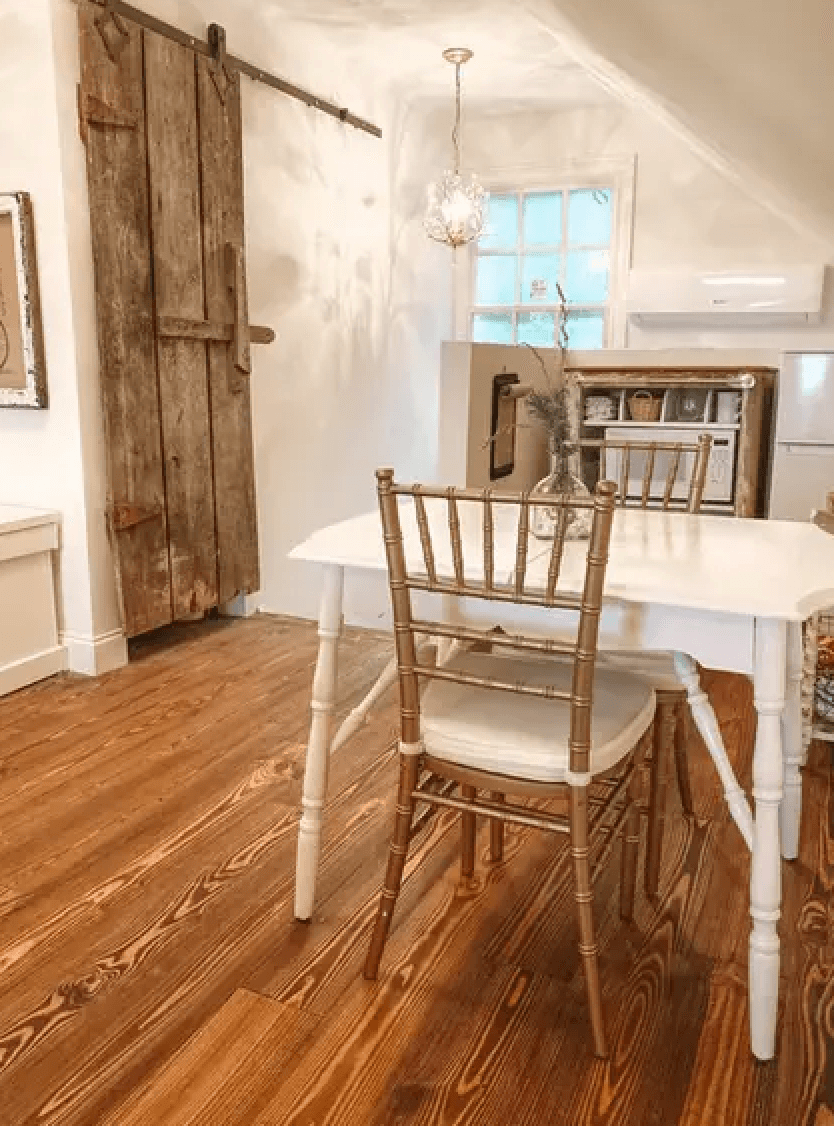 A cozy dining area featuring a white table, a gold chair, and a rustic wooden sliding door.