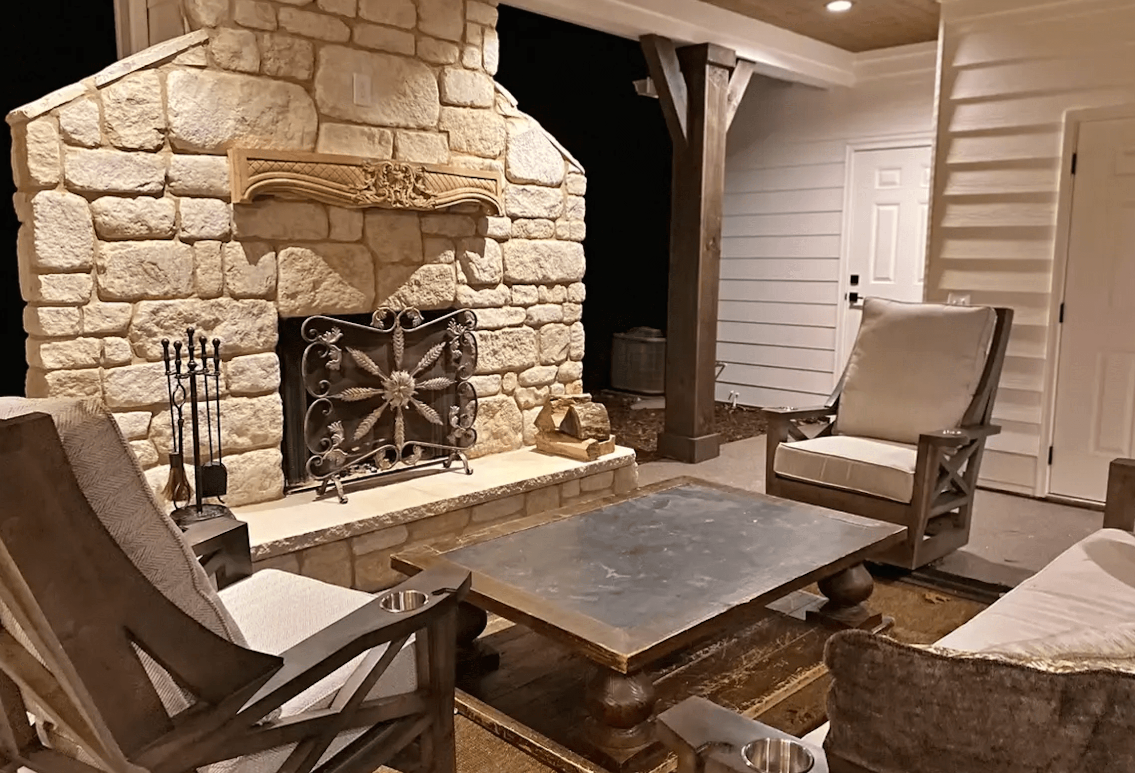 Cozy outdoor seating area featuring a stone fireplace and wooden furniture.