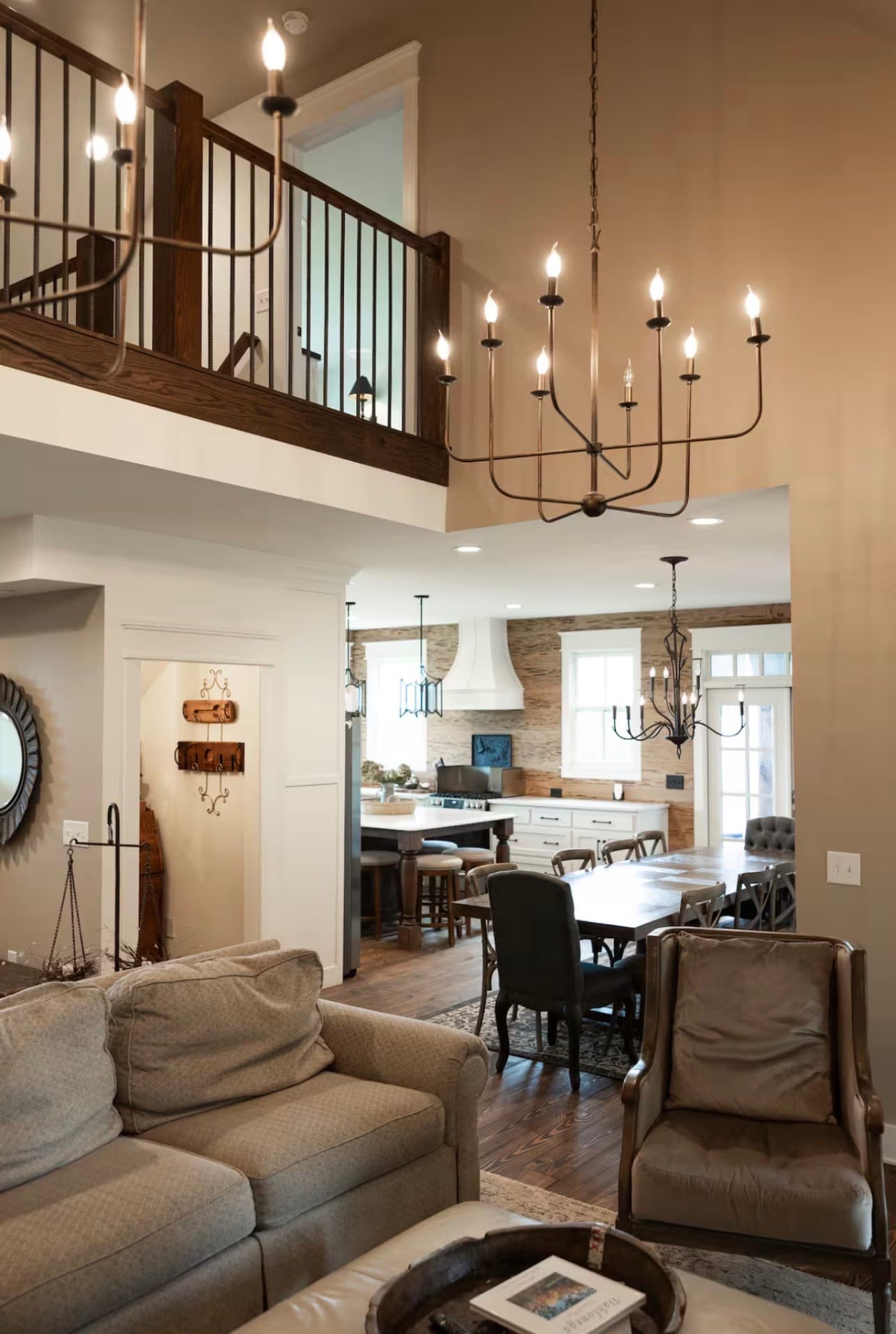 A cozy living area featuring a sofa, armchairs, and a view into a well-lit kitchen and dining space.