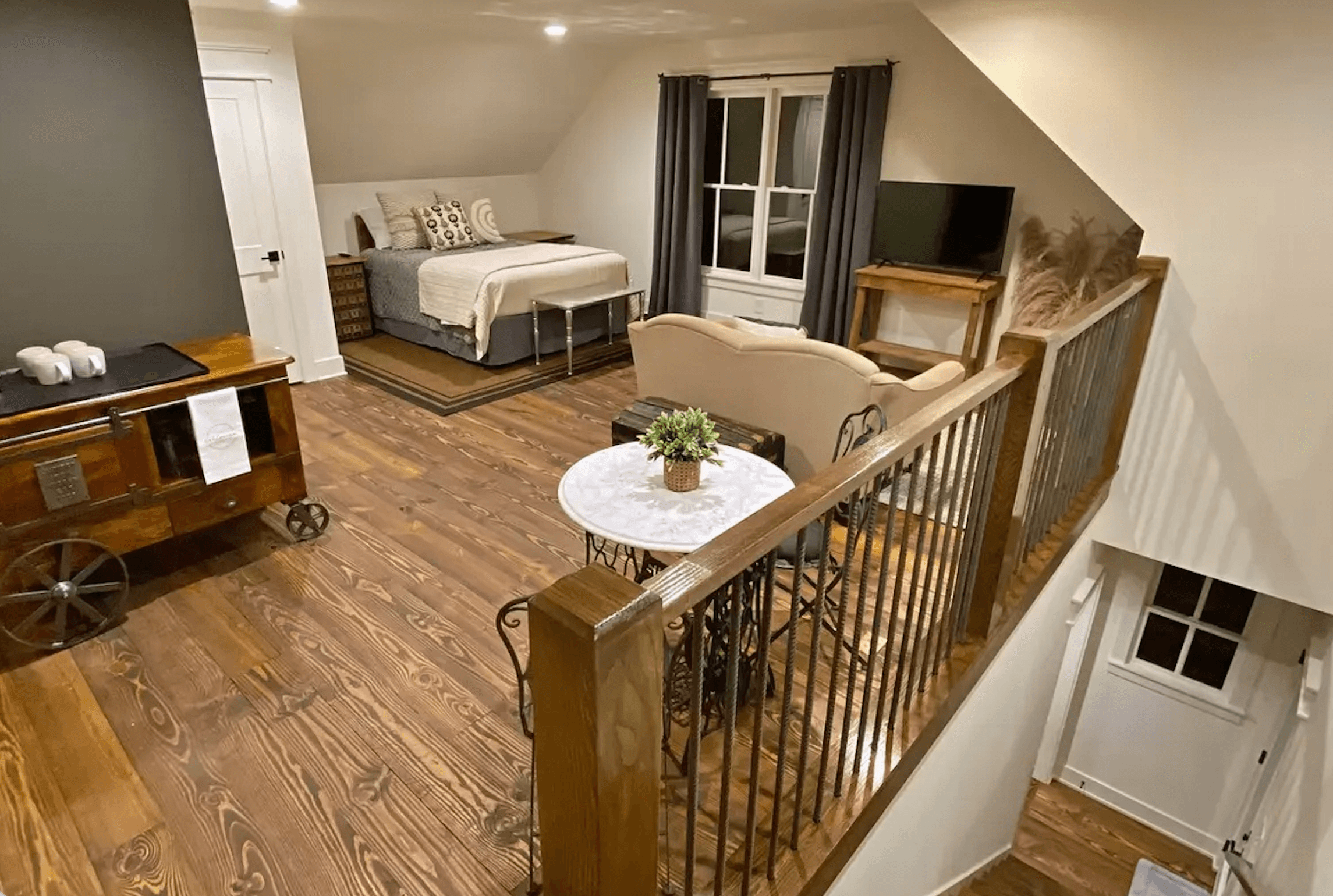 Cozy loft bedroom with a bed, seating area, and wooden floors.