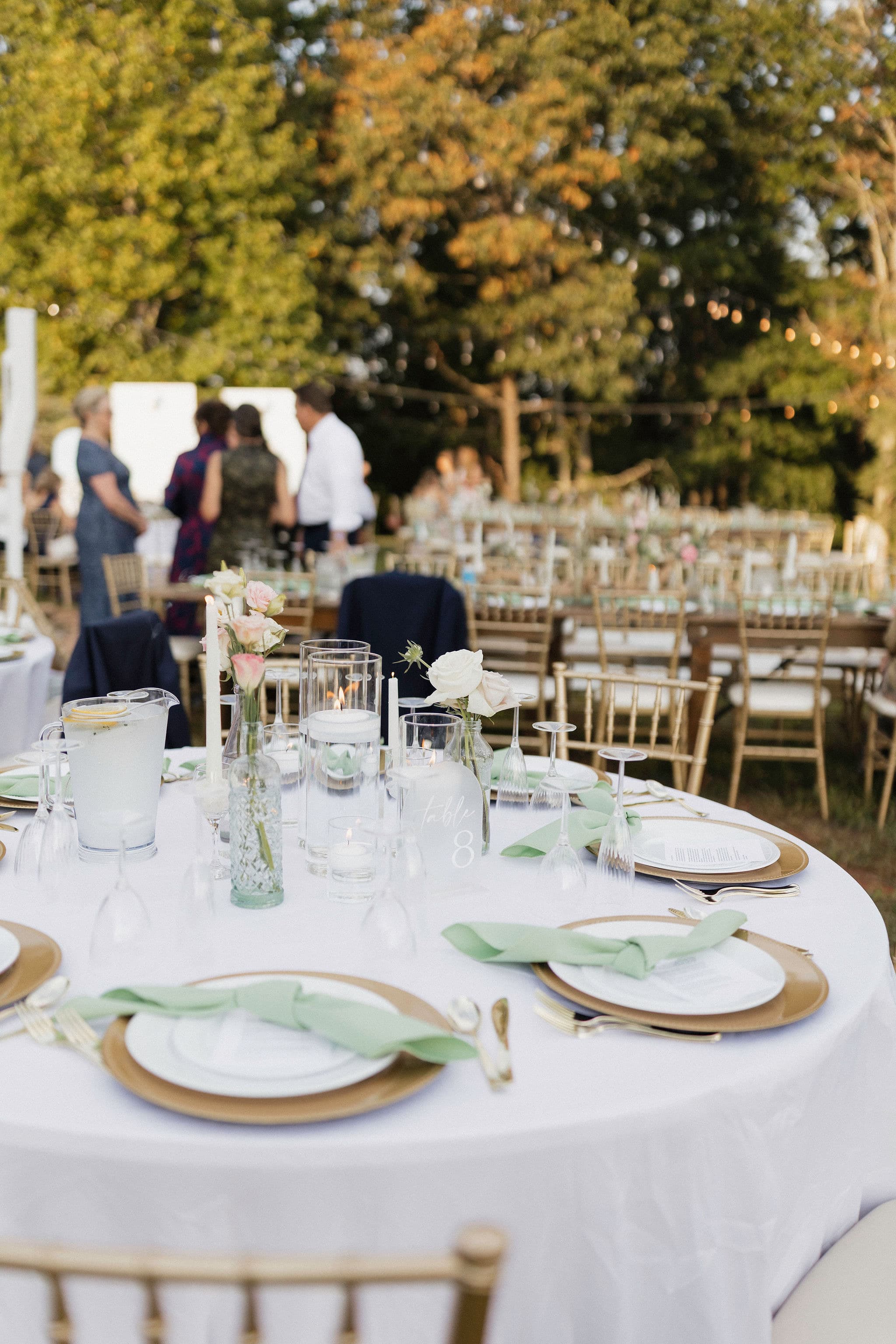 A beautifully set outdoor dinner table adorned with floral arrangements and elegant dinnerware.