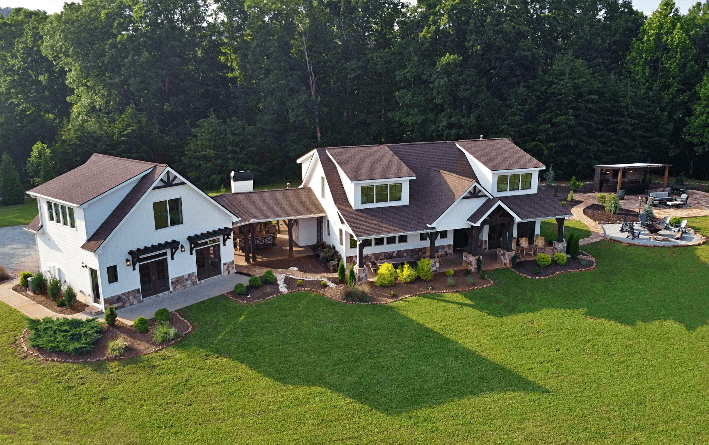 Aerial view of a spacious, modern white house with a landscaped yard and patio area.